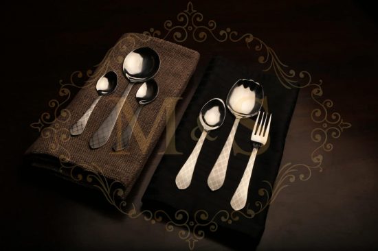 Complete aura essential classic cutlery set placed on brown and black cloth.