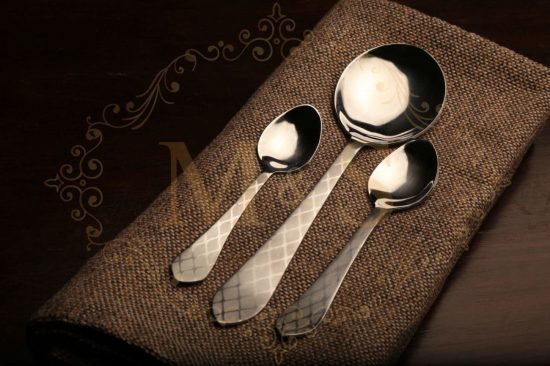 Teaspoon,curry serving spoon and tablespoon placed on brown cloth.