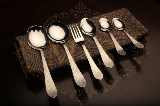 Complete aura essential classic cutlery set placed on brown cloth.
