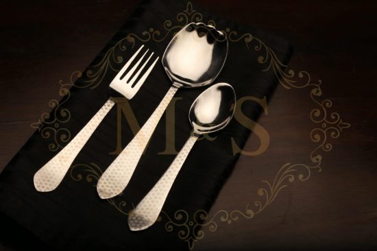 Fork,serving spoon and tablespoon placed on black cloth.