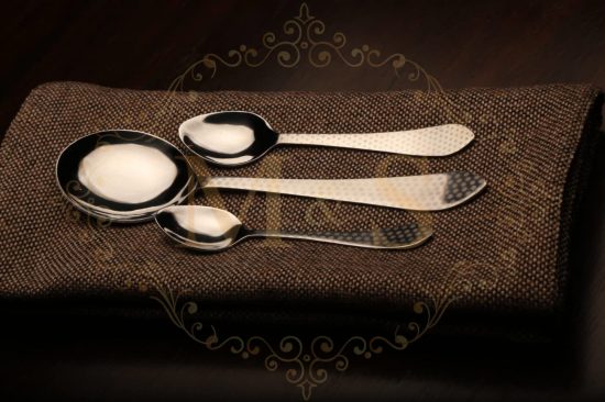 Teaspoon,serving spoon and tablespoon placed on brown cloth.