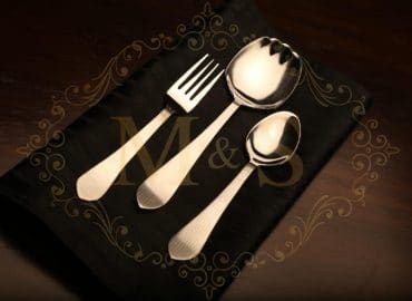Fork,serving spoon and tablespoon placed on black cloth.