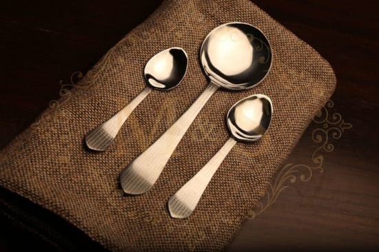 dessert spoon,serving spoon and teaspoon placed on brown cloth.