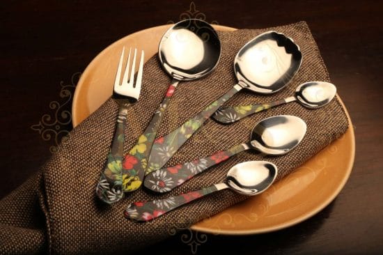 Fork and complete range of spoons on plate over brown cloth.