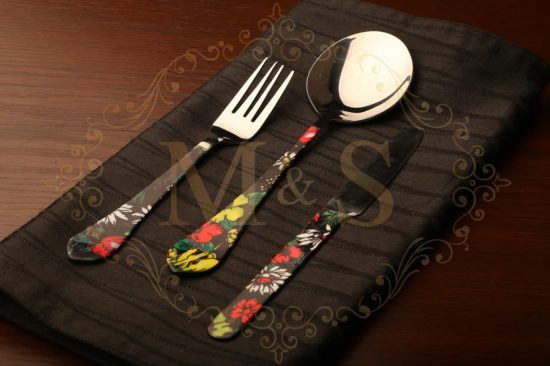 Fork,serving spoon and butter knife placed on black cloth.
