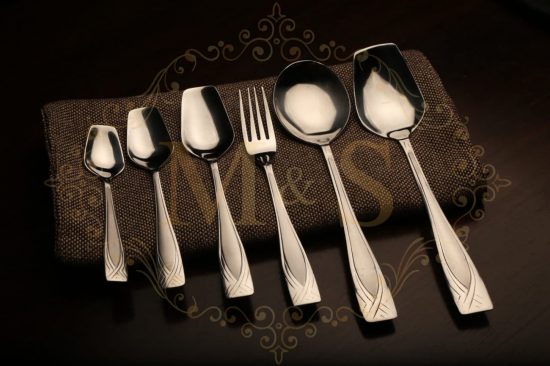 Complete vintage silver arch cutlery set placed on brown cloth.