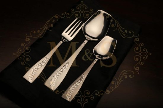 Fork,rice serving spoon and tablespoon placed on black cloth.