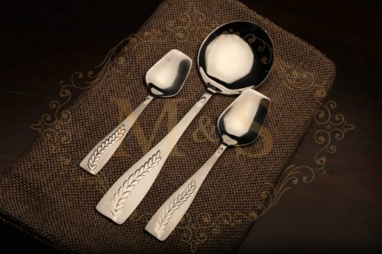 Dessert spoon,serving spoon and teaspoon placed on brown cloth.