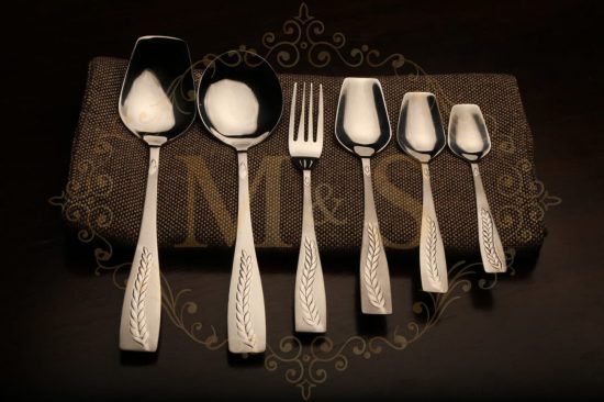Complete cutlery set of vintage silver barlay placed on brown cloth.
