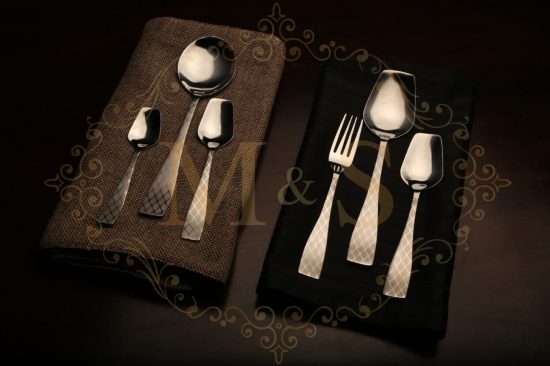 Complete vintage silver classic cutlery placed on a black and brown cloth.