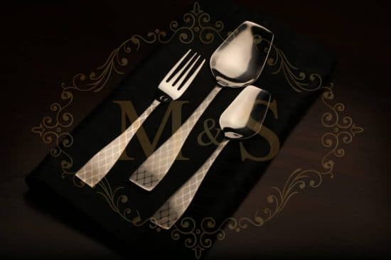 Fork,rice serving spoon and tablespoon placed on a black cloth.