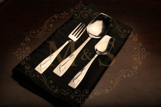 Fork,rice serving spoon and tablespoon placed on black cloth.
