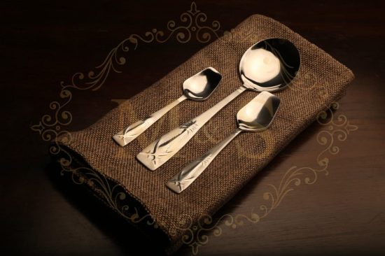 Dessert spoon,serving spoon and teaspoon placed on brown cloth.