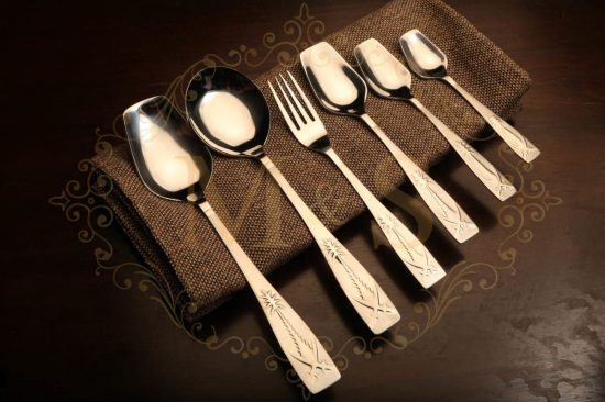 Complete vintage silver palm cutlery set placed on brown cloth.