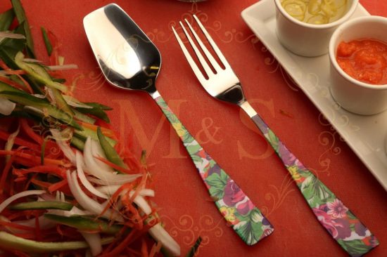 Flower designed spoon and fork with vegetables placed on the left